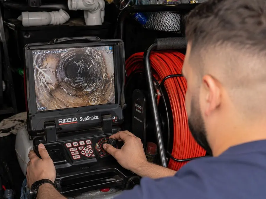 Plumber examining a CCTV drain inspection monitor, Beaumaris